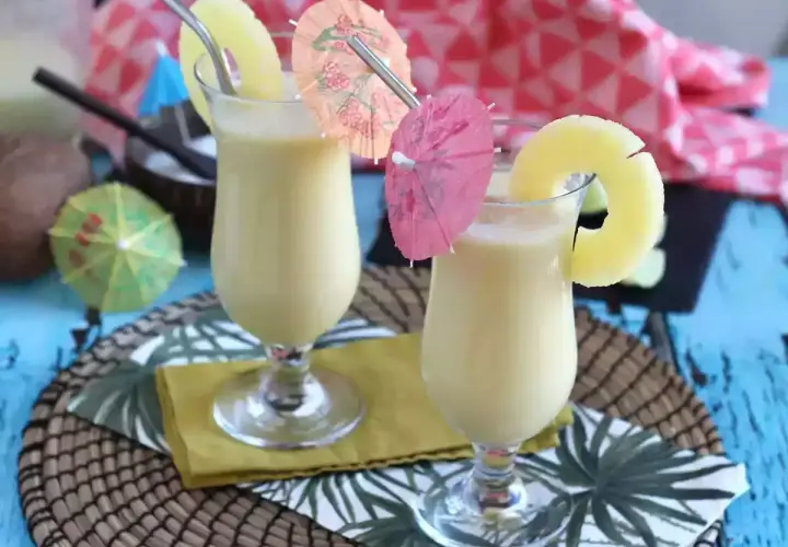 Dwa orzeźwiające koktajle pina colada z plasterkiem ananasa i parasolkami. Idealne na letnie popołudnie.