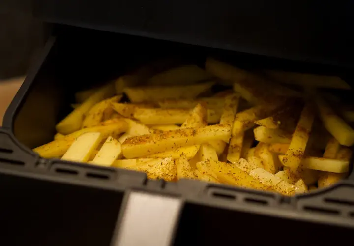 Ziemniaki pokrojone w frytki, przyprawione i gotowe do pieczenia w airfryerze. Pyszne dania z airfryer to szybki sposób na chrupiące frytki.