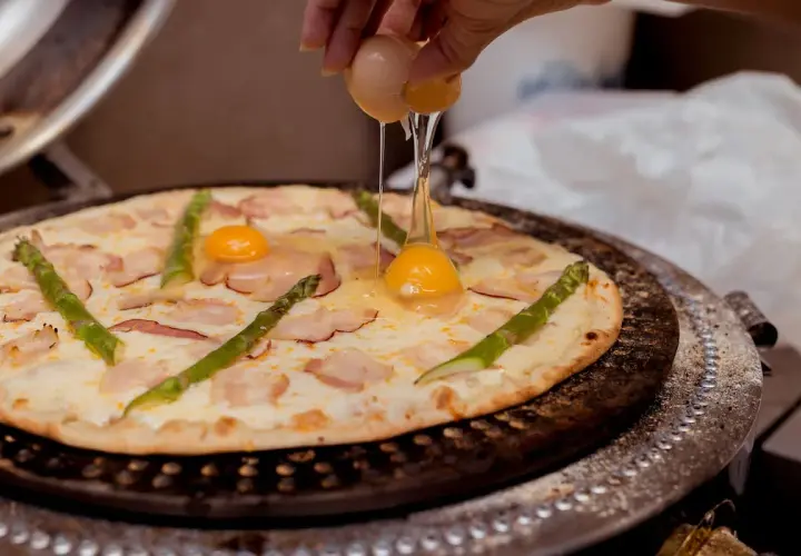Na pizzę z boczkiem i szparagami dodawane jest jajko.