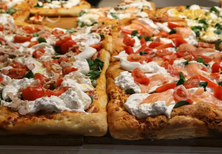 Dwie prostokątne pizze z burratą, pomidorkami i łososiem lub tuńczykiem. Puszyste ciasto, kremowy ser i świeże dodatki kuszą swoim wyglądem.