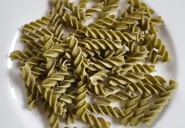 Zielony makaron fusilli z zielonego groszku, ułożony na białym talerzu. Idealny do lekkiego i zdrowego posiłku.