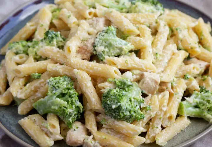 Penne z kurczakiem i brokułami w kremowym sosie, posypane parmezanem. Pyszne danie obiadowe.