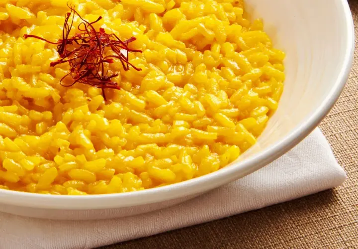 Aksamitne risotto alla milanese, złociste i aromatyczne, ozdobione nitkami szafranu.
