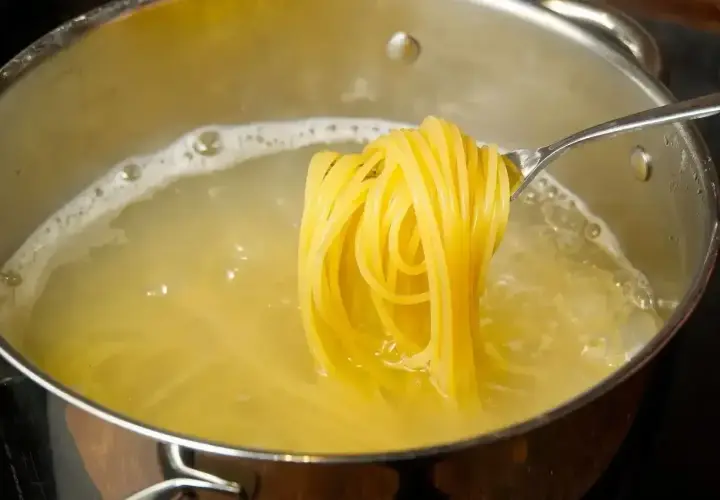 Złociste spaghetti na widelcu, gotujące się w wodzie. Pyszny posiłek, który może być niskokaloryczny, jeśli zwrócimy uwagę na spaghetti kcal.