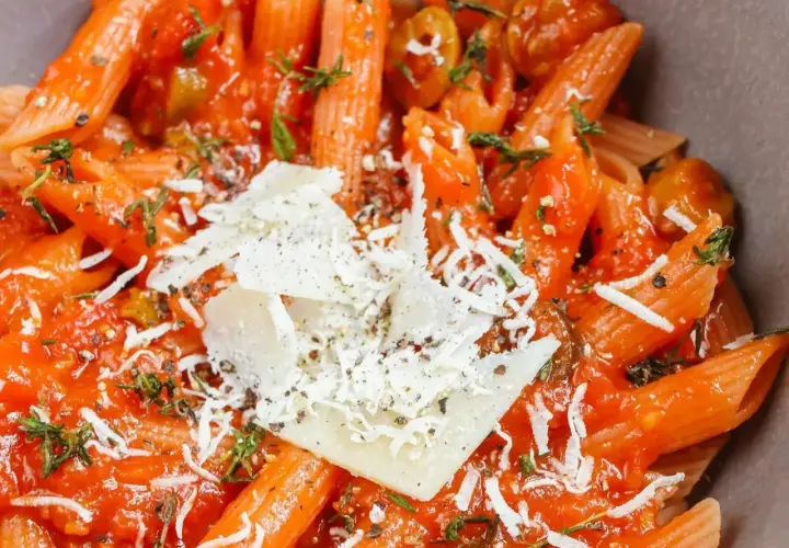 Penne w sosie pomidorowym z parmezanem i ziołami. Pyszne danie z makaronem, które zachwyca smakiem i aromatem.