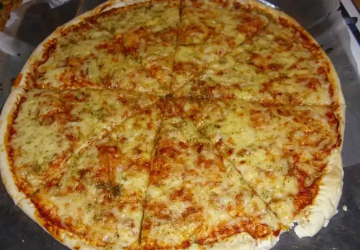 Pyszna margarita pizza z roztopionym serem i aromatycznymi ziołami, pokrojona na 8 kawałków.
