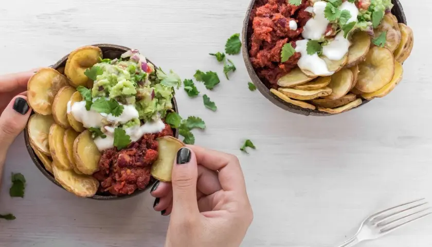 Dwie miski z guacamole, fasolą i chipsami z ziemniaków. Ziemniaki kcal w zdrowej odsłonie.