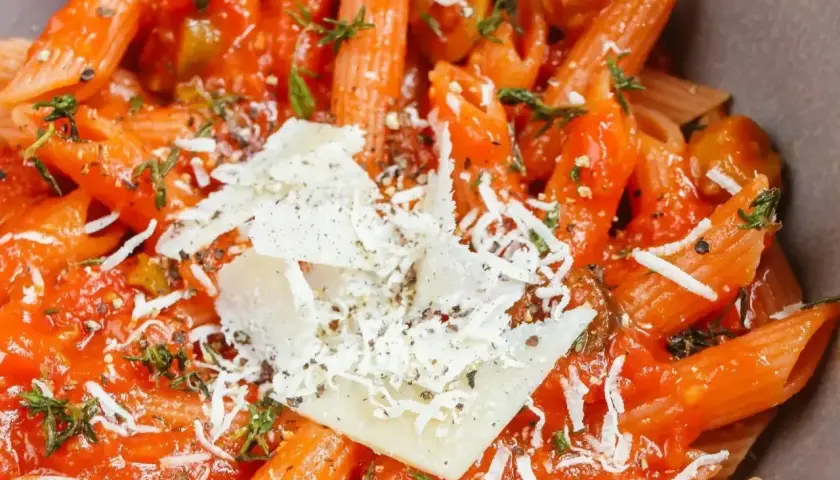 Penne w sosie pomidorowym z parmezanem i ziołami. Ta pyszna potrawka wygląda apetycznie.