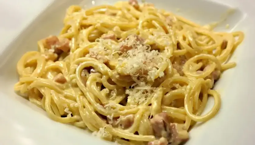 Pyszne spaghetti carbonara z kawałkami guanciale i parmezanem. Idealna śmietana do carbonary to sekret tego dania.