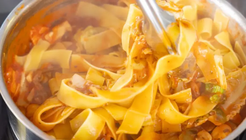 Gorący, parujący makaron pappardelle z sosem pomidorowym i warzywami, gotowy na szybki obiad z makaronem.
