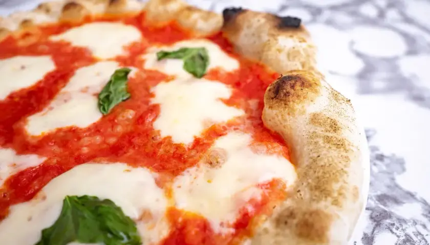 Pyszna pizza Margherita, klasyczny włoski przepis. Idealnie wypieczone ciasto, sos pomidorowy, mozzarella i świeża bazylia.