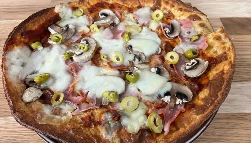 Pyszna pizza z twarogu z pieczarkami, szynką i oliwkami, zapieczona na złoto.