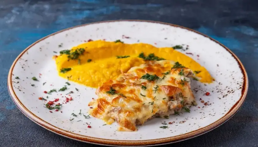Pyszne katsu z serem zapieczonym na wierzchu, podane z purée z dyni i posypane ziołami.