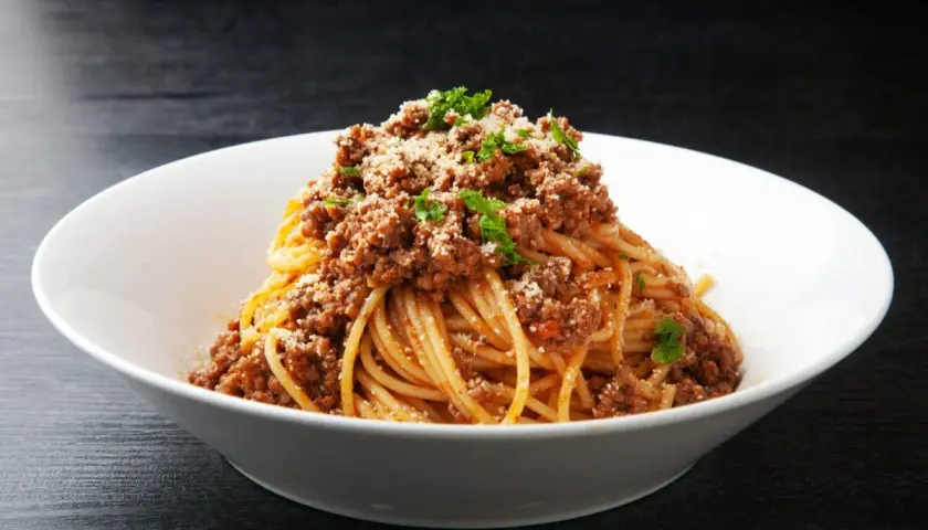 Pyszne spaghetti z mięsem mielonym, posypane parmezanem i natką pietruszki. Idealny prosty przepis na obiad.