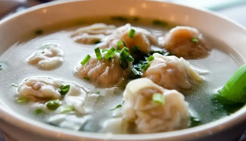 A miseczce paruje aromatyczna zupa won ton, ozdobiona szczypiorkiem.