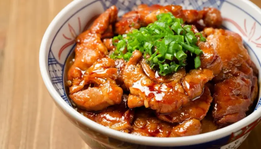 Miseczka z kurczakiem soboro w sosie teriyaki, posypana szczypiorkiem.