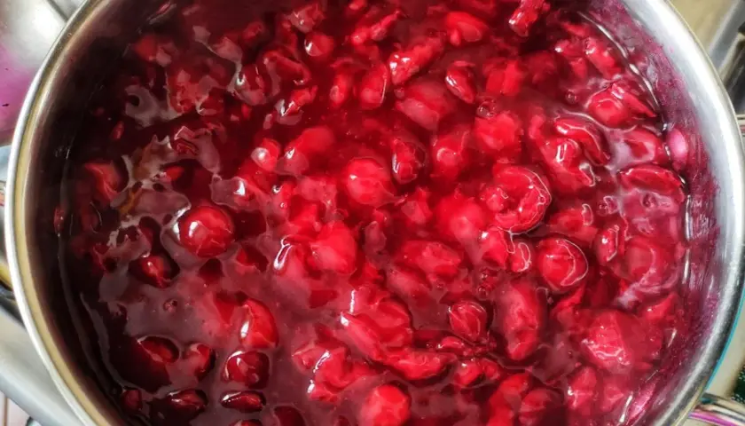 Gęsta, błyszcząca frużelina wiśniowa w metalowym garnku, gotowa do podania.