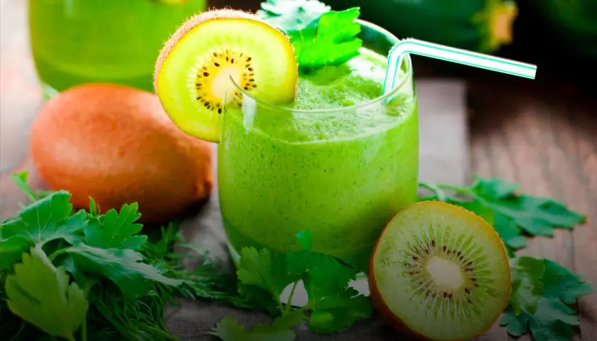 Zielony koktajl z kiwi i ziołami, udekorowany plasterkiem kiwi.