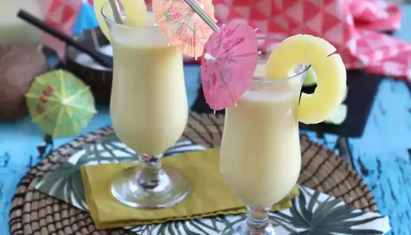 Dwa orzeźwiające koktajle pina colada z plasterkiem ananasa i parasolkami. Idealne na letnie popołudnie.