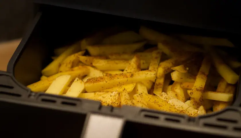 Ziemniaki pokrojone w frytki, przyprawione i gotowe do pieczenia w airfryerze. Pyszne dania z airfryer to szybki sposób na chrupiące frytki.