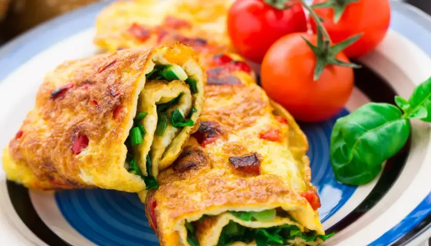 Roladki z omletu z zielonymi warzywami i pomidorkami koktajlowymi. Pyszne śniadanie bez chleba.