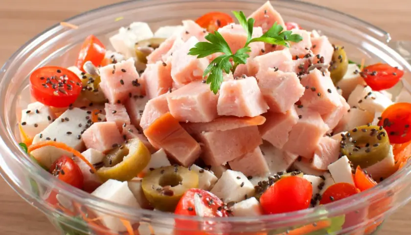 Pyszna, lekka sałatka z wędzonym kurczakiem, pomidorkami koktajlowymi, oliwkami i serem feta, posypana nasionami chia.