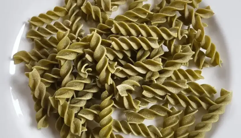 Zielony makaron fusilli z zielonego groszku, ułożony na białym talerzu. Idealny do lekkiego i zdrowego posiłku.