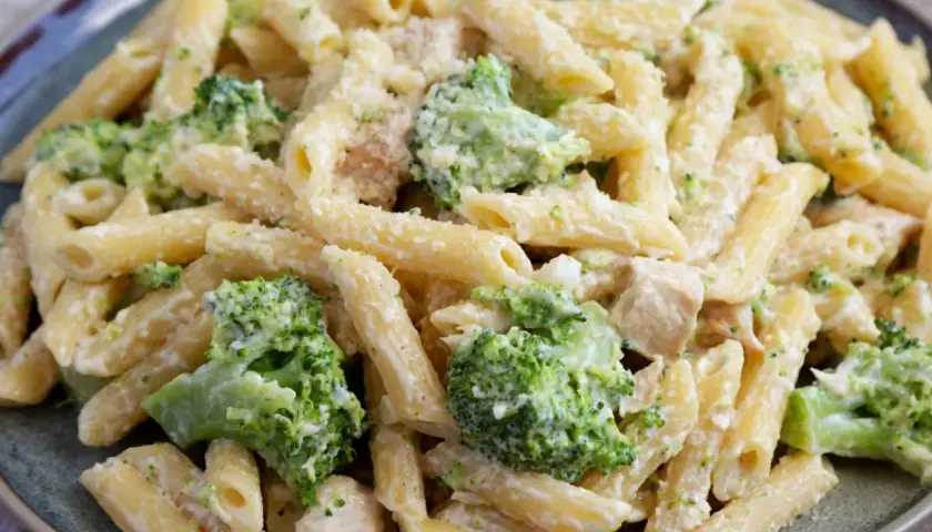 Penne z kurczakiem i brokułami w kremowym sosie, posypane parmezanem. Pyszne danie obiadowe.