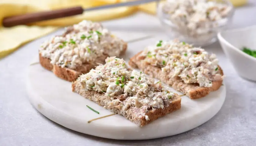 Trzy kromki ciemnego chleba z obfitym smarowidłem z makreli i twarogu, posypane szczypiorkiem. Idealna pasta na kanapki.
