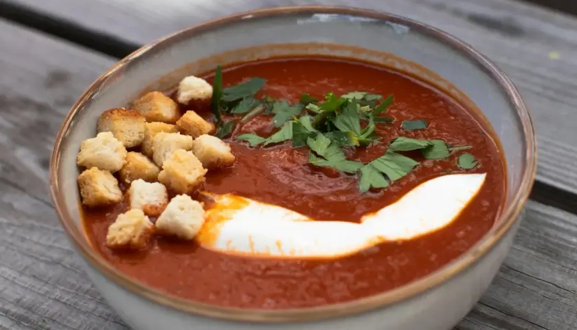 Aksamitny pomidorowy krem, przypominający smakiem butter masala, z grzankami, śmietaną i natką pietruszki.