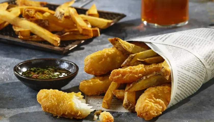 Chrupiące ryby i złociste frytki, idealne na fish and chips przepis. Podane z sosem i piwem.