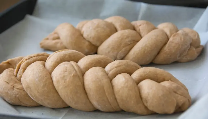 Dwie plecione chałki na papierze do pieczenia. Zastanawiasz się nad chałka kcal?