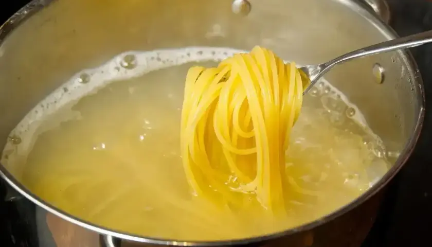 Złociste spaghetti na widelcu, gotujące się w wodzie. Pyszny posiłek, który może być niskokaloryczny, jeśli zwrócimy uwagę na spaghetti kcal.