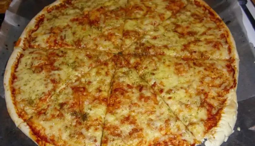 Pyszna margarita pizza z roztopionym serem i aromatycznymi ziołami, pokrojona na 8 kawałków.