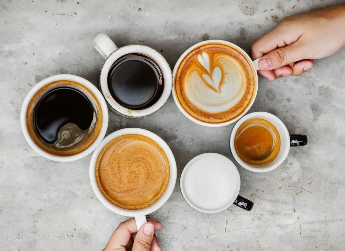Różne rodzaje kawy, od espresso po latte, ułożone na szarym blacie. Czy kawa wypłukuje magnez? To pytanie nurtuje wielu miłośników tego napoju.
