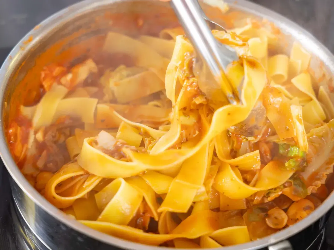 Gorący, parujący makaron pappardelle z sosem pomidorowym i warzywami, gotowy na szybki obiad z makaronem.