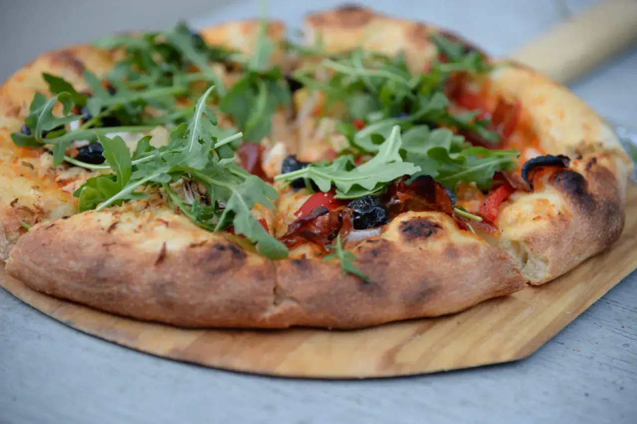 Pyszna pizza z rukolą i oliwkami, idealna na podstawie z przepisu na ciasto do pizzy.