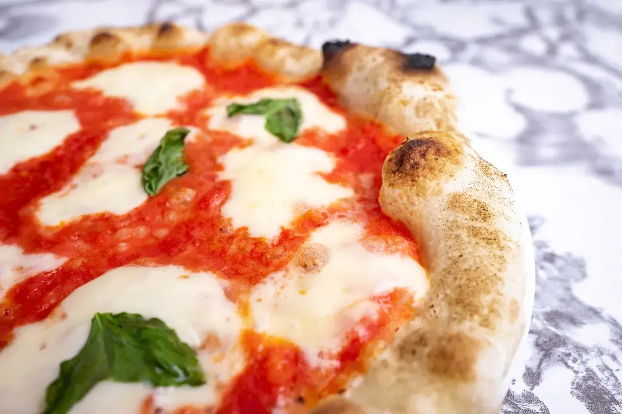 Pyszna pizza Margherita, klasyczny włoski przepis. Idealnie wypieczone ciasto, sos pomidorowy, mozzarella i świeża bazylia.