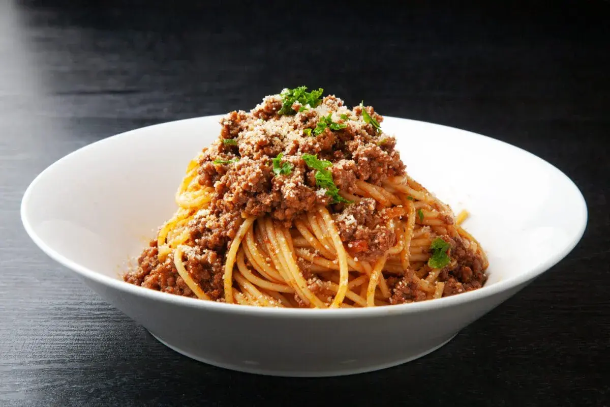 Pyszne spaghetti z mięsem mielonym, posypane parmezanem i natką pietruszki. Idealny prosty przepis na obiad.