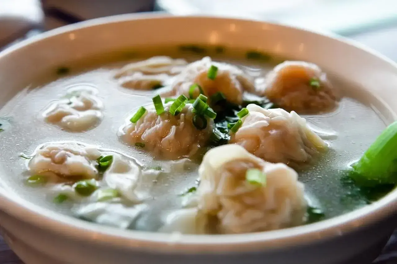 A miseczce paruje aromatyczna zupa won ton, ozdobiona szczypiorkiem.