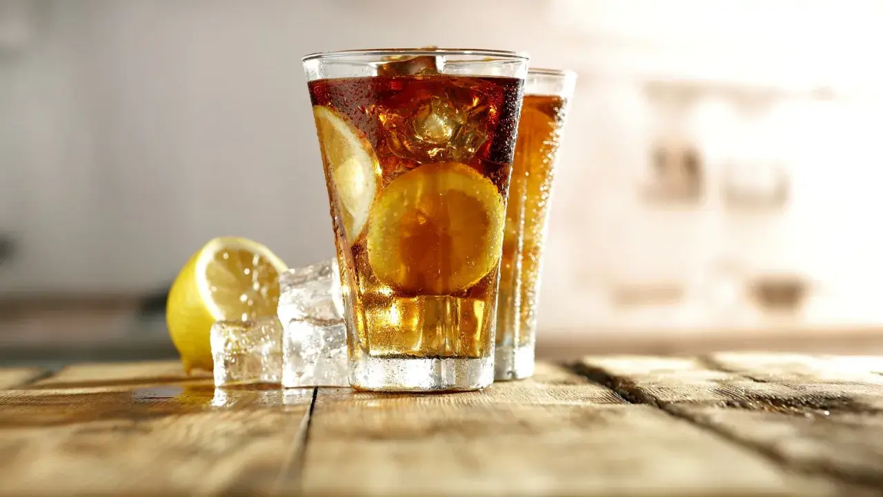 Orzeźwiający Long Island Ice Tea z cytryną i lodem na drewnianym blacie.