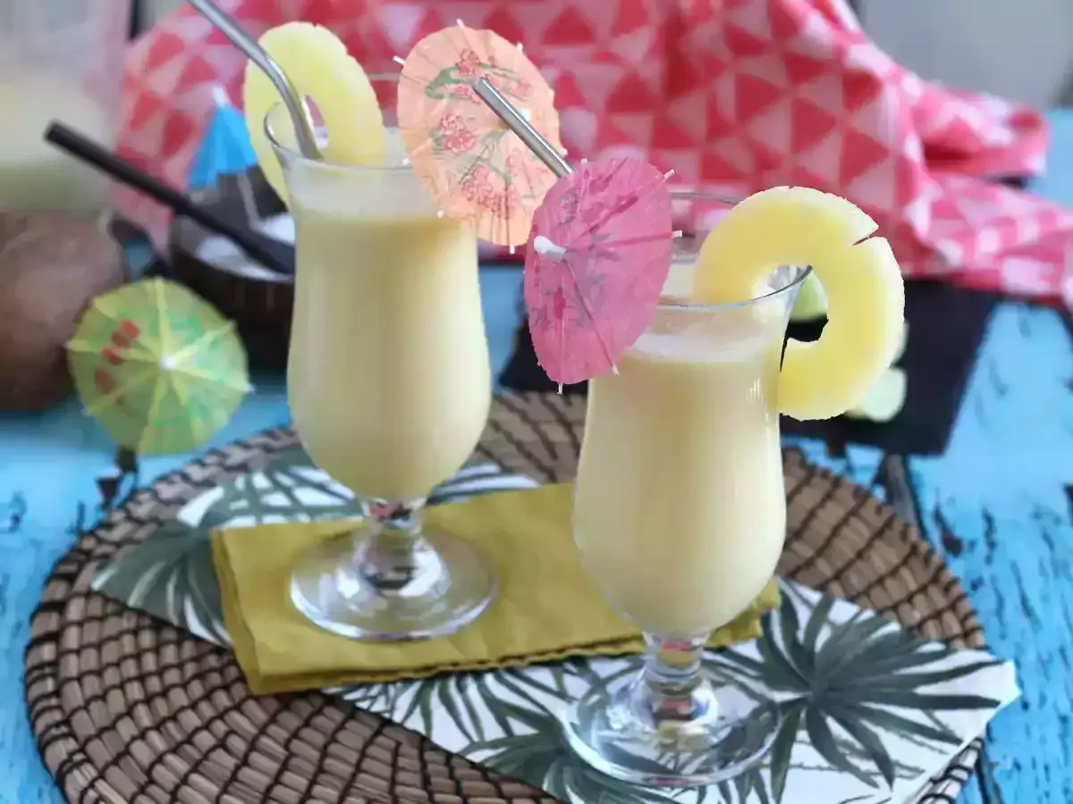 Dwa orzeźwiające koktajle pina colada z plasterkiem ananasa i parasolkami. Idealne na letnie popołudnie.