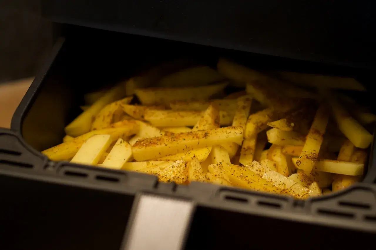 Ziemniaki pokrojone w frytki, przyprawione i gotowe do pieczenia w airfryerze. Pyszne dania z airfryer to szybki sposób na chrupiące frytki.
