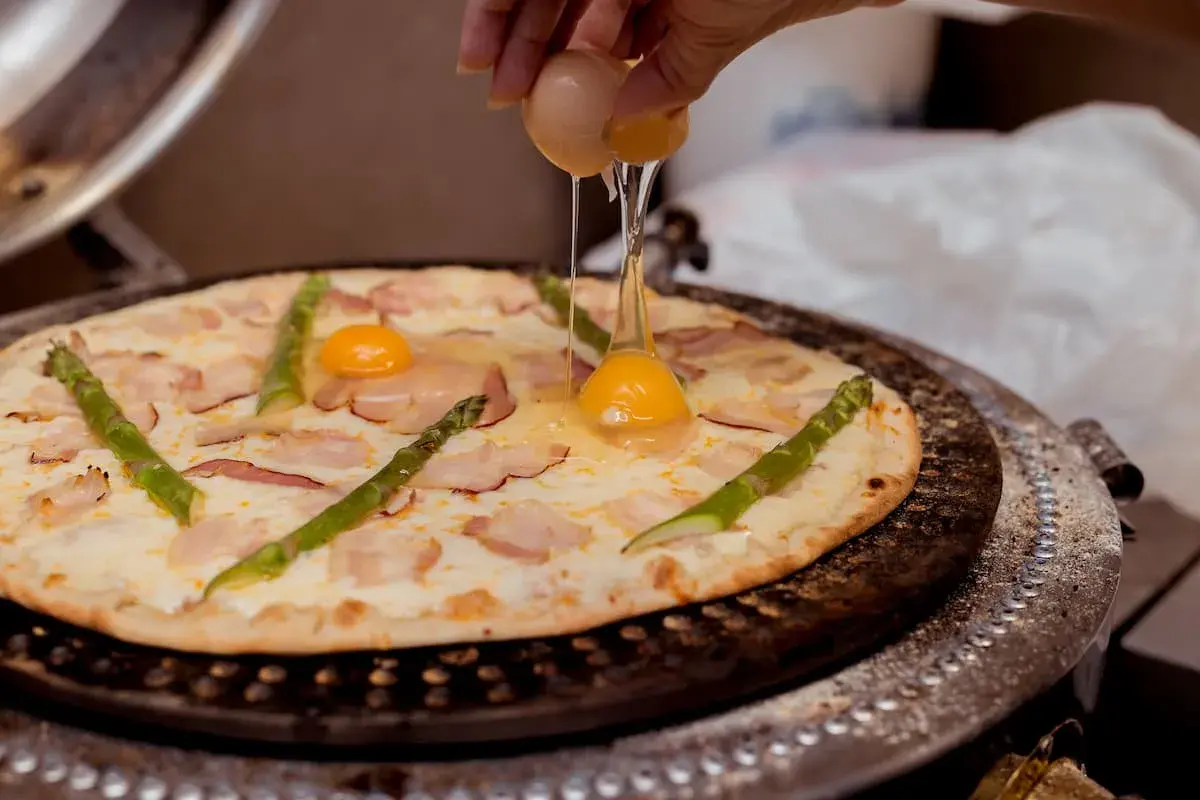 Na pizzę z boczkiem i szparagami dodawane jest jajko.