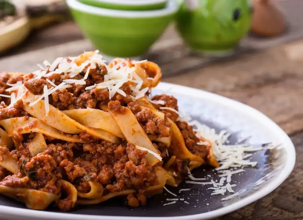 Pyszne tagliatelle z sosem bolognese, posypane parmezanem. Idealne danie, gdy zastanawiasz się, ile smażyć mięso mielone do spaghetti.