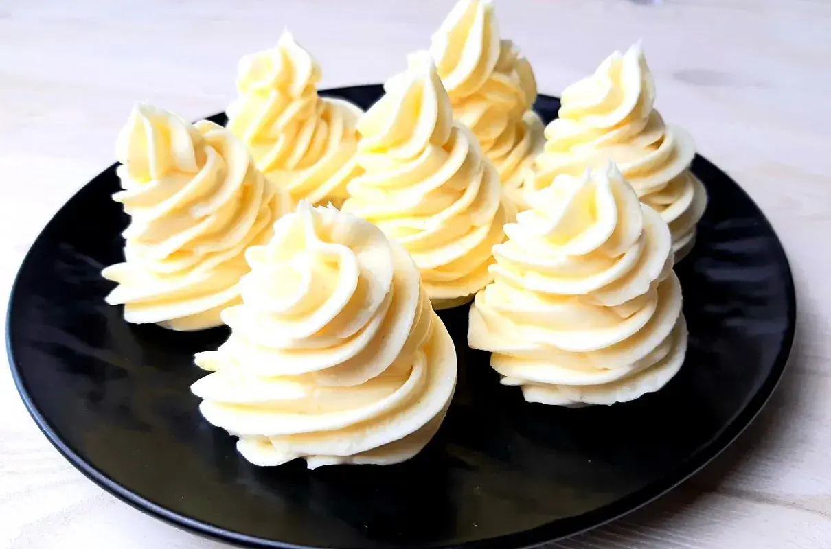 Na czarnym talerzu ułożono osiem porcji najprostszego kremu budyniowego, uformowanych w kształt stożków.