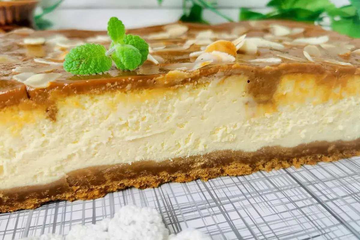 Pyszny sernik z mascarpone i budyniem, z polewą karmelową i migdałami. Idealny przepis na deser.