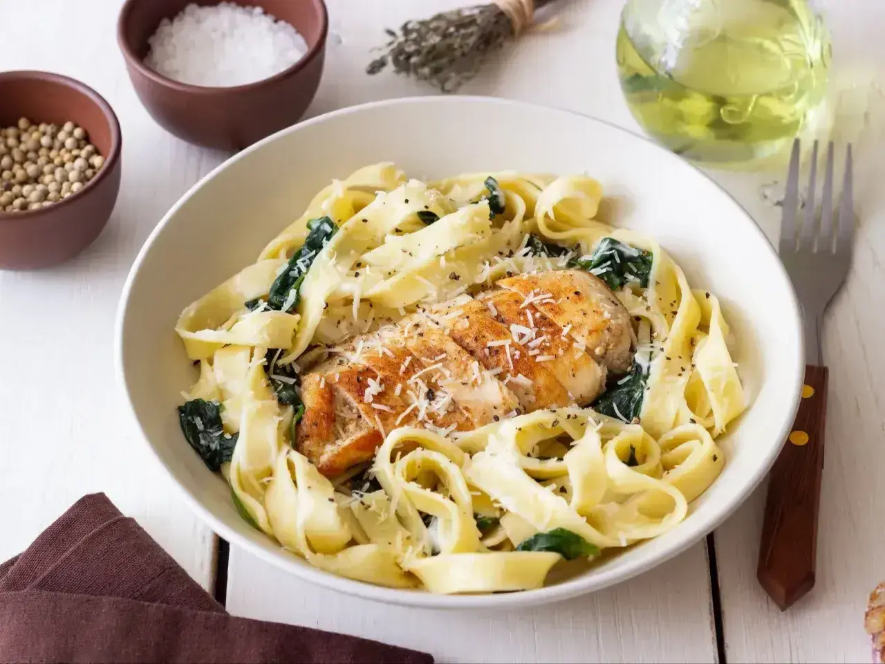 Pyszny makaron z kurczakiem i szpinakiem, posypany parmezanem. Idealny na szybki obiad.