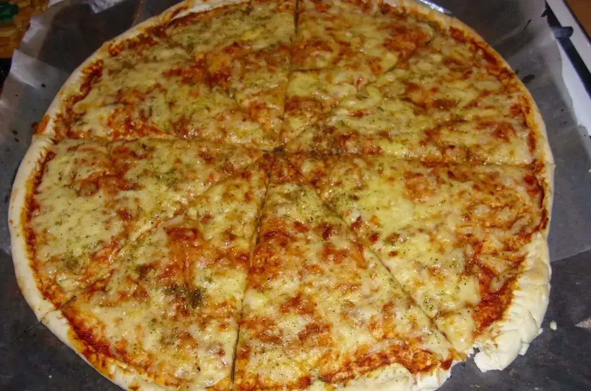 Pyszna margarita pizza z roztopionym serem i aromatycznymi ziołami, pokrojona na 8 kawałków.