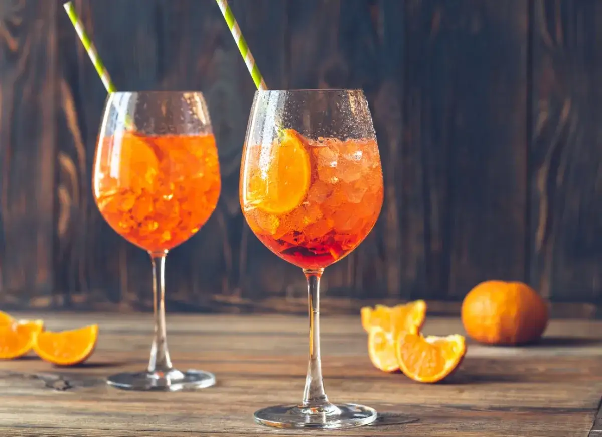 Dwa orzeźwiające Aperol Spritz z plasterkiem pomarańczy i słomką. Idealny aperitif, prosty aperol przepis.